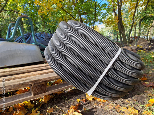 Slika na platnu A coiled black corrugated pipe is on the project site