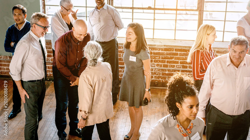 Photography Diverse group of people networking in a sunlit brick-walled room.