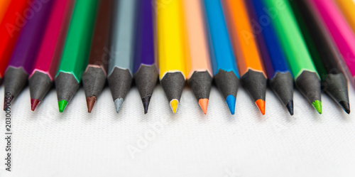 Colorful pencils arranged in a row on a white surface for various drawing activities