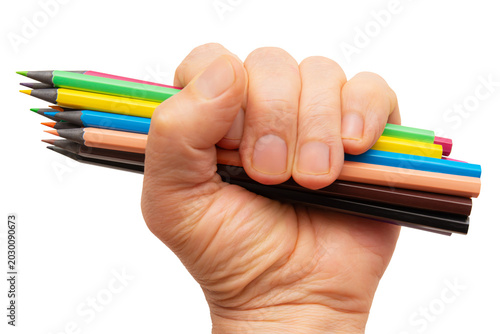 Hand holds several colored pencils tightly in a fist showing vibrant colors and tools for drawing
