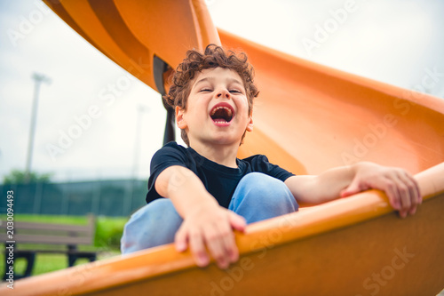 фотографія Happy kid slide on playground on summer season