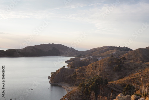 Beautiful scenic landscape of a tranquil lake surrounded by terraced rolling hills at sunset, highlighting adventure travel, nature tourism and destination exploration in South America.