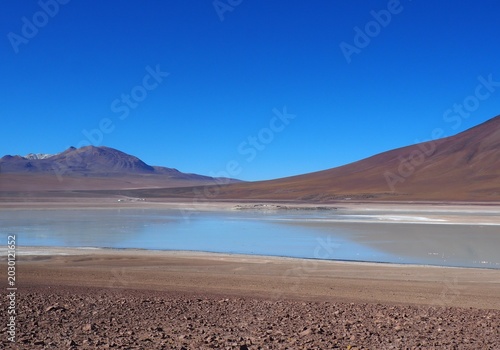 Spectacular high altitude turquoise lagoon surrounded by volcanic mountains in the Bolivia Altiplano desert, ideal for adventure travel, nature tourism, wilderness exploration and active lifestyle.