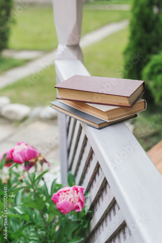 Cuadro en lienzo Stacked hardcover books on wooden porch railing near blooming pink peonies in ga