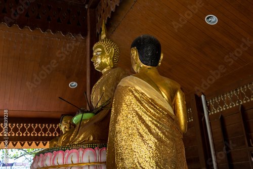 Photos Gilded Buddha statues in a serene temple interior, bathed in soft light casting gentle shadows on ornate wooden ceilings and intricate carvings, exuding spiritual tranquility and cultural heritage