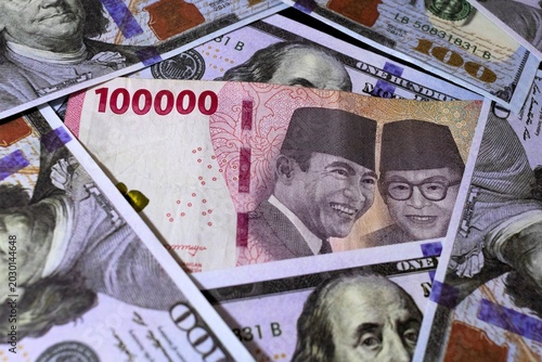 High angle shot of IDR currency surrounded by USD paper money, symbolizing exchange rates or inflation.