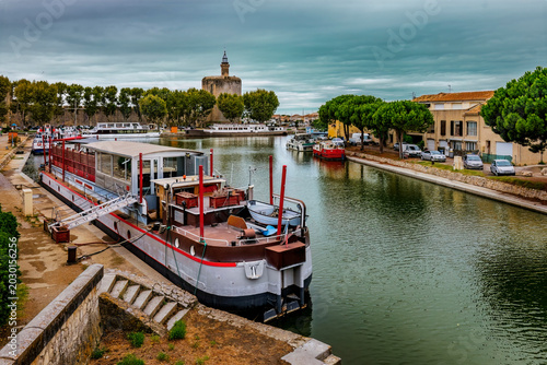 Canvas Print Canal and moored riverboat in Aigues-Mortes, Camargue, France, with medieval wal