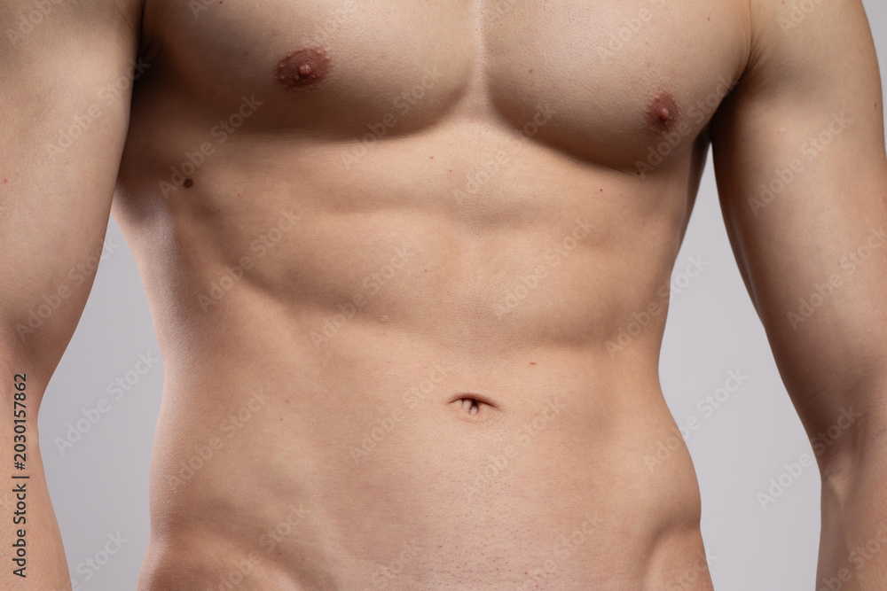 Fototapeta premium A young man with an elastic torso and prominent muscles is dressed in tight jeans after sports. Concept: body parts, men's health. The flexible and agile body of a dancer or athlete