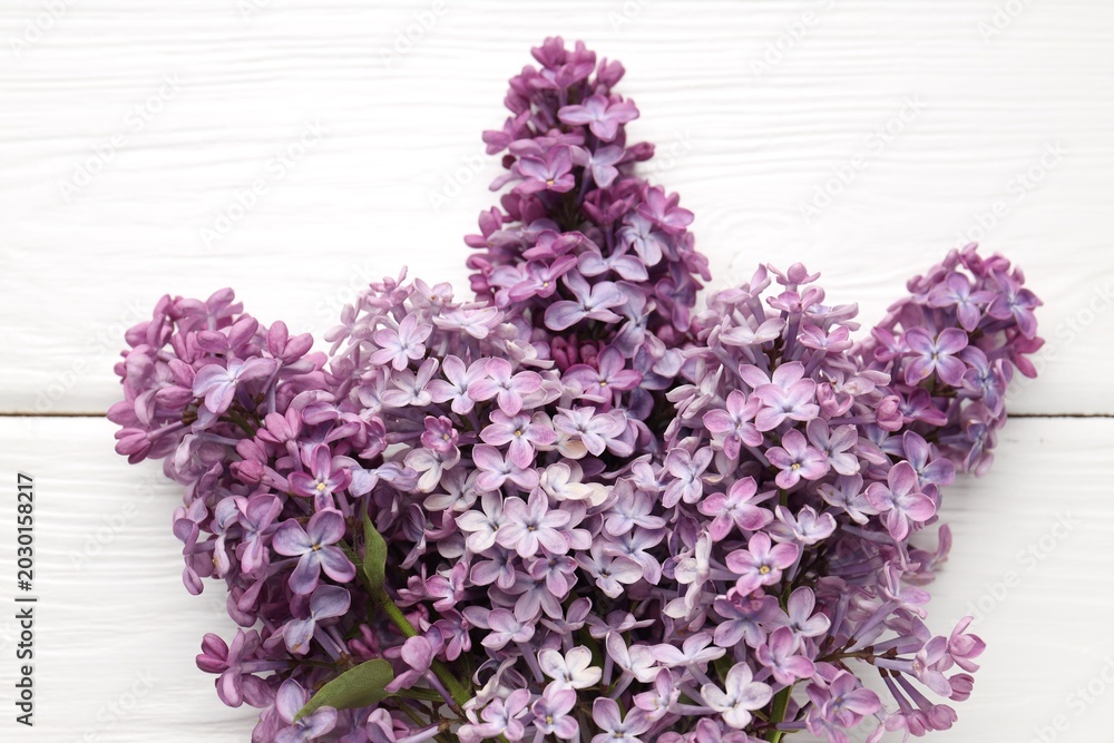 Obraz premium Branches with tender lilac flowers on white wooden table, top view
