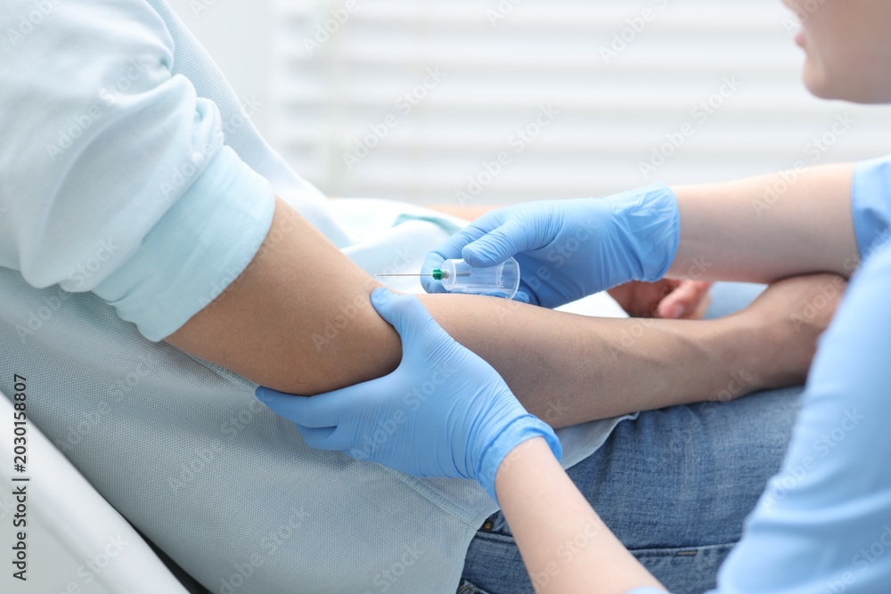 Obraz premium Nurse drawing blood sample of patient's vein with syringe in clinic, closeup
