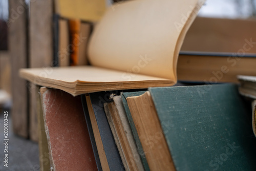 Foto Top view of old antique and secondhand books piled haphazardly on asphalt ground, illustrating a flea market selection, garage sale clutter, or secondary paper waste recycling