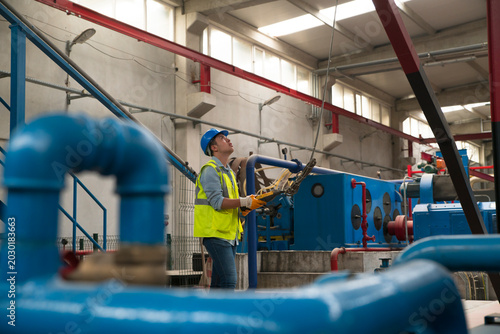 Foto Industrial worker inspecting equipment and performing maintenance in a factory