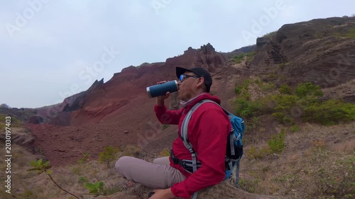 Thirsty hiker drinking water at red earth mines in puebla mexico