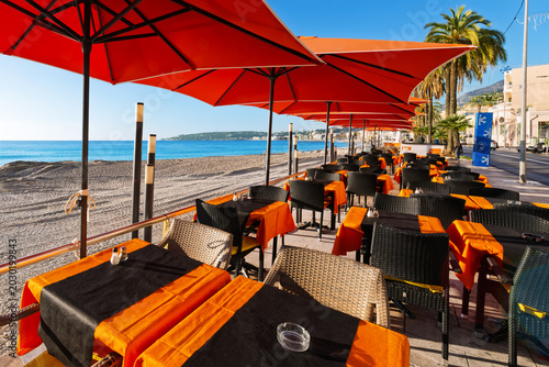 A seaside cafe along the Plage du Casino, the sandy beach along the Mediterranean Sea and Promenade du Soleil at the resort town of Menton, France, along the Cote d'Azur French Riviera.