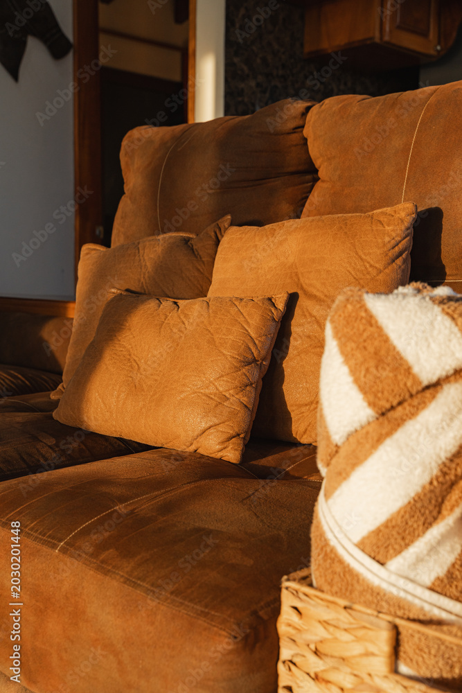 Фотография Cozy brown sofa receiving warm sunset light