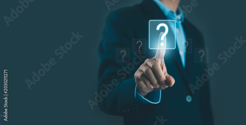 Businessman touching glowing question mark icon on virtual screen, symbolizing FAQ, problem solving, decision making, support, and business uncertainty. Modern technology interface with copy space.