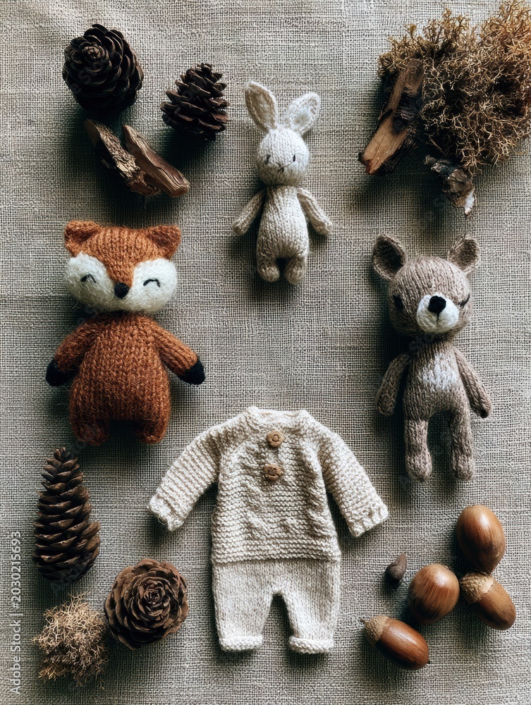 Obraz premium Woodland forest theme baby shower scene features plush toys, a small knit onesie, and natural items arranged on a linen surface.