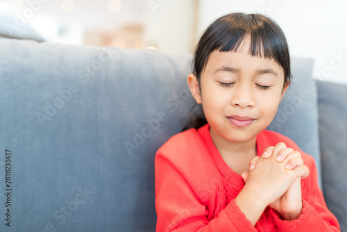Tableau sur toile Asian little girl smiling and closing eyes while she prays
