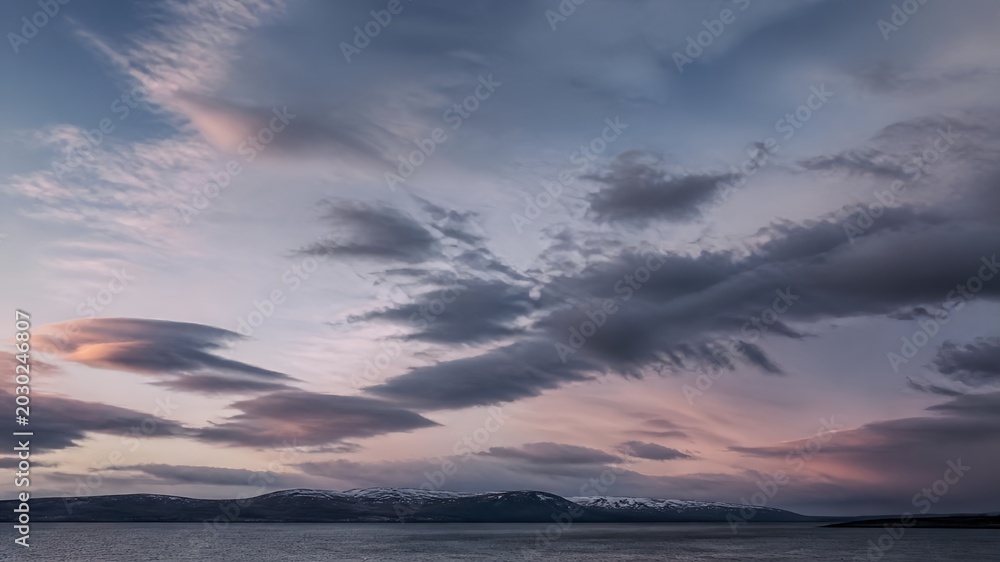 Fototapeta premium Sunburst Breaking Through Dramatic Storm Clouds Over Peaceful Ocean with Pastel Pink Horizon