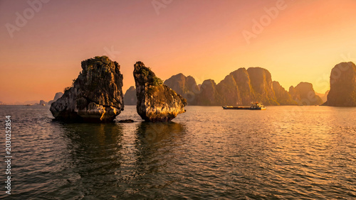Fotografie Karst islands and barge at sunset in Ha Long Bay Vietnam
