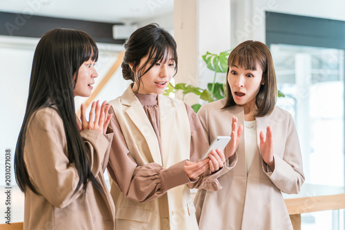 Foto A businesswoman boss and her subordinate are surprised when they look at a smartphone