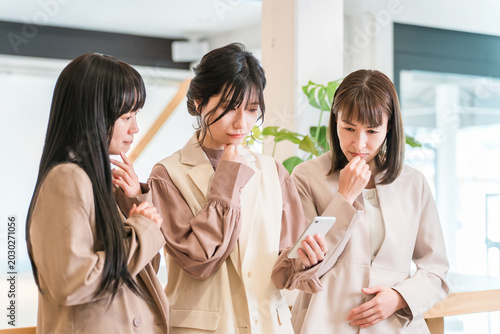 Cuadro en lienzo A businesswoman boss and her subordinate are both troubled while looking at their smartphones