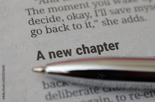 A new chapter text on book page with silver pen macro shot for business concept
