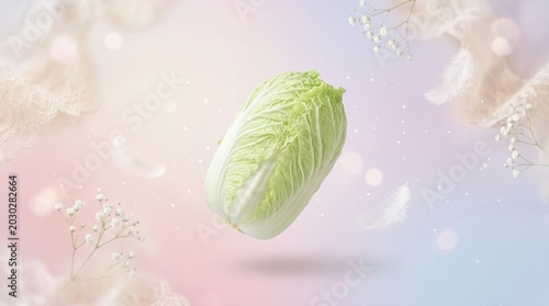 A vibrant napa cabbage floats gracefully against a soft, pastel background. Delicate white flowers and feathers surround the cabbage, creating a dreamy and ethereal atmosphere.