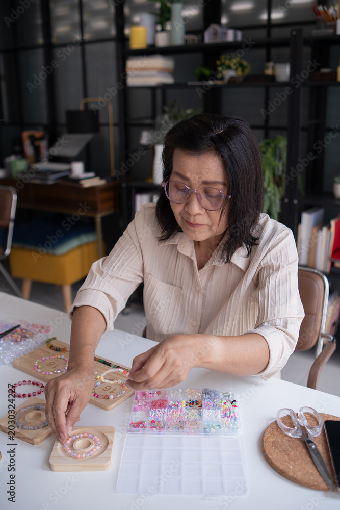 Fototapeta premium Mature asian woman making handmade jewellery accessories handcraft hobby