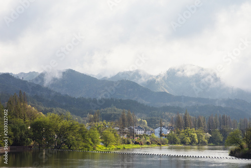 The mountains beside the river are shrouded in mist.