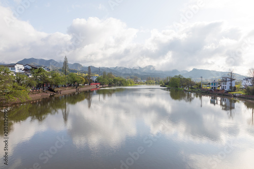 The mountains beside the river are shrouded in mist.
