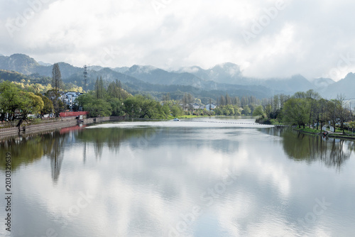 The mountains beside the river are shrouded in mist.