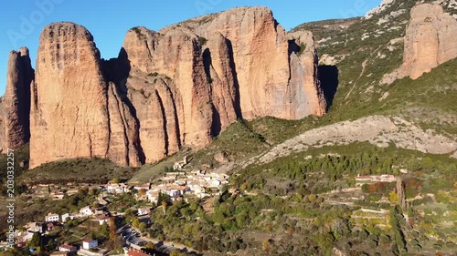 Mallos de Riglos. Huesca, Aragon, Spain. Orage Mountains with vertical walls and a white village at their foot. Aerial view. Famous climbing area. Hiking trail Camino del Cielo (Path of Heaven).