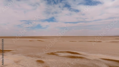 Aerial drone shot over the dry Chott el Djerid salt lake. Cinematic perspective of the vast crystalline salt flats under a cloudy sky in southern Tunisia, North Africa