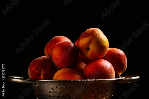 Photos Colander with sweet ripe peaches on black background