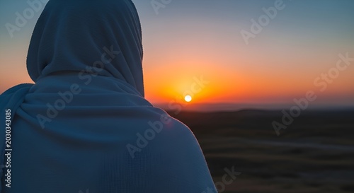 Person in white hijab looking at desert sunset, peaceful contemplation, warm orange sky