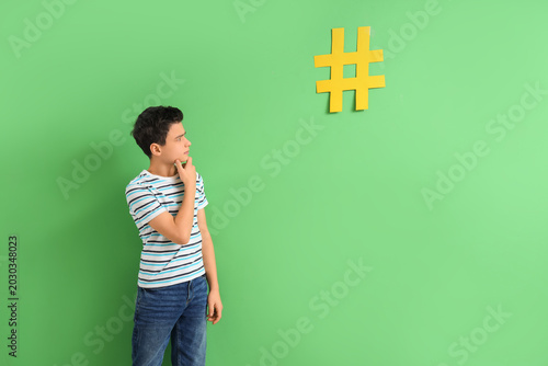 Thoughtful teenage boy with hashtag on green background