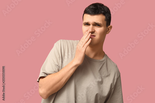 Foto Handsome young man feeling bad smell on pink background