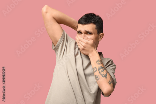 Obraz na płótnie Handsome young man feeling bad smell from armpits on pink background
