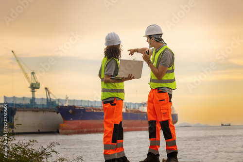 Obraz na plátně Industrial logistic engineers with laptop checking cargo ship operations at cont