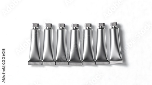 Seven silver metal tubes with caps on white background