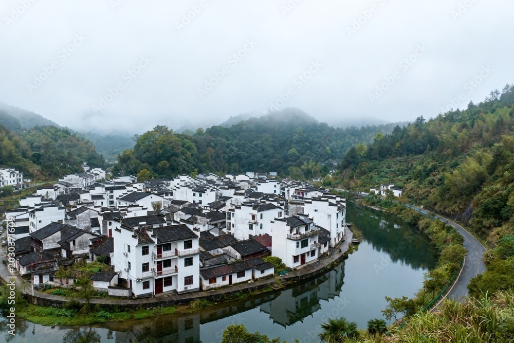 Obraz premium Traditional village by river in misty mountains