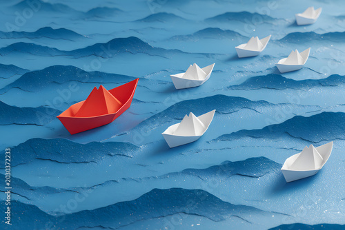 Leadership concept, red leader boat with white paper boats floating in the blue waves of the sea