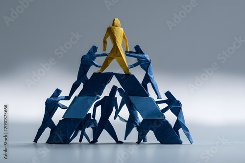 Team forming a structured origami triangle with the leader at the top empowering the base, modern symbolic structure