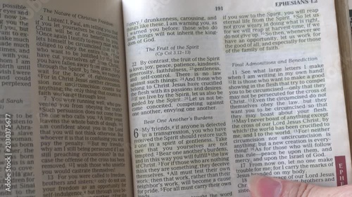 Holy Bible open up to the book of Galatians of the new testament, zooming into Chapter 5 verse 22 on the fruit of the Spirit. New Revised Standard Version.