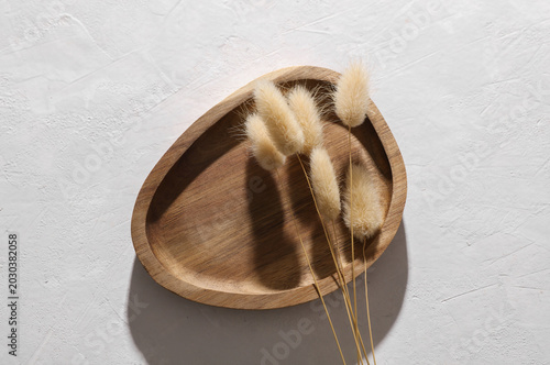 Premium wooden tray with dry grass on white concrete background