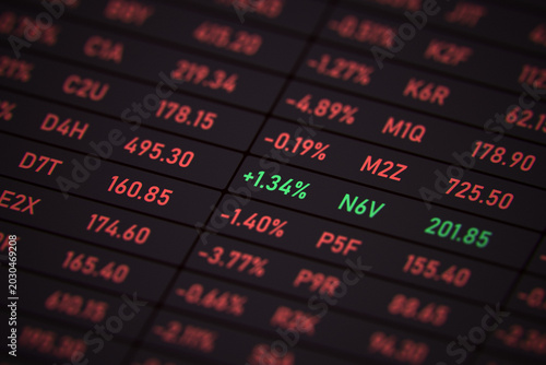 Photos Close-up of a digital stock market ticker display screen showing a bearish market in red with one profitable green stock outperforming the trend