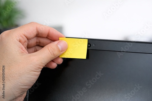 A person holds a yellow post-it note, ready to jot down an idea or reminder