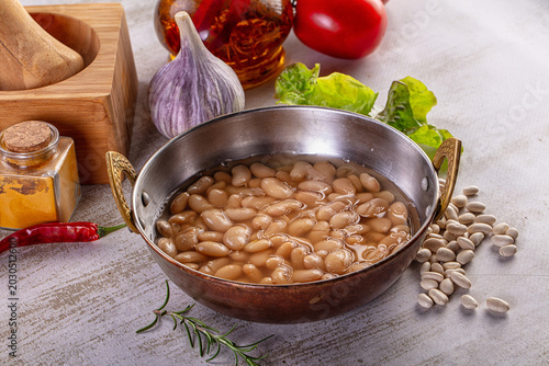 Tableau sur toile Cooked white beans in a rustic metal bowl surrounded by fresh ingredients for a healthy meal