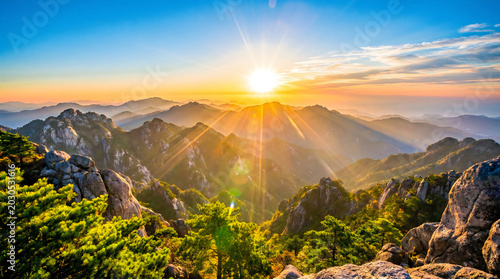 Golden sunrise over mountain peaks and rocky terrain